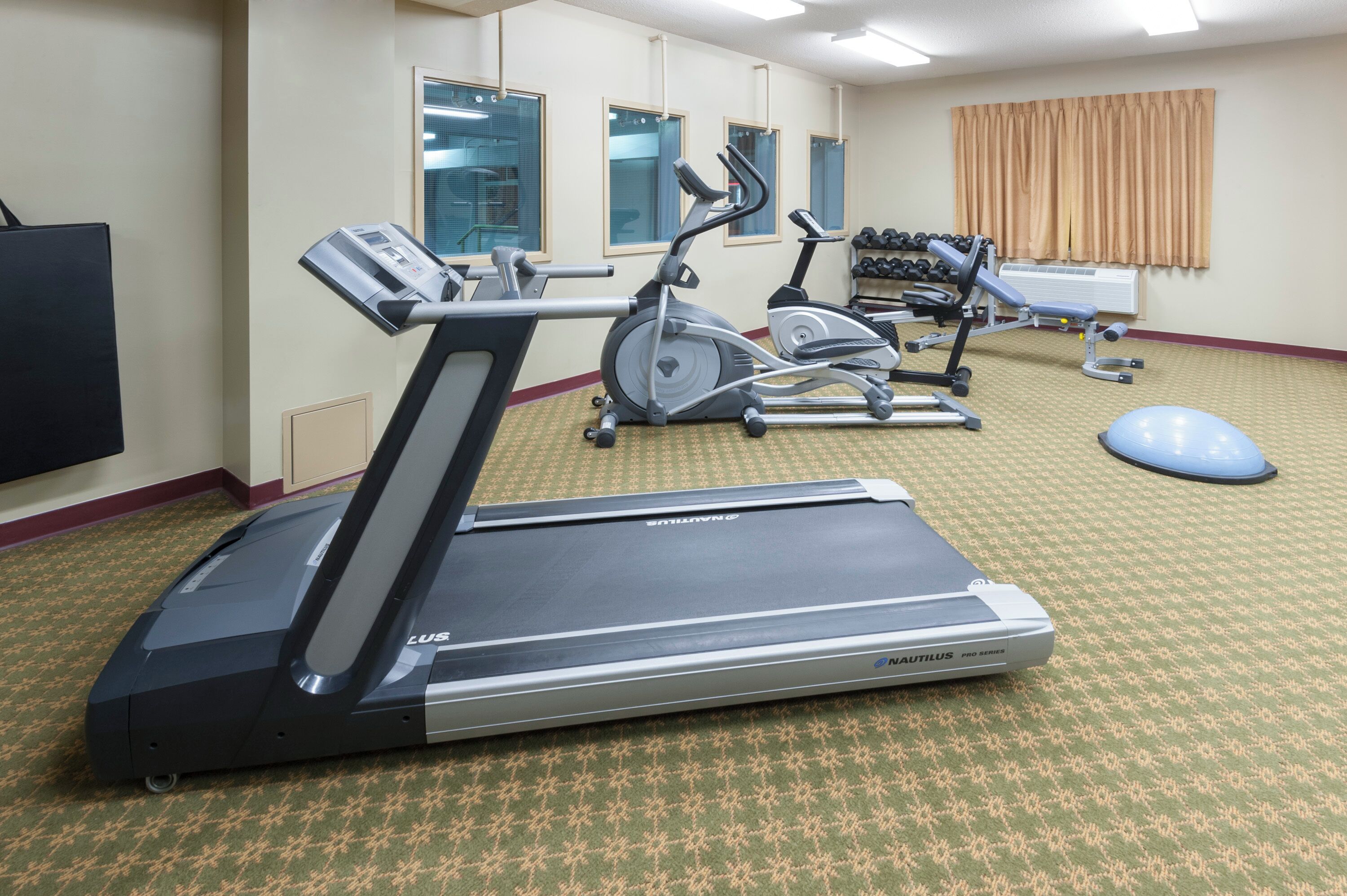 A fitness room with treadmills, an elliptical, and a rowing machine.