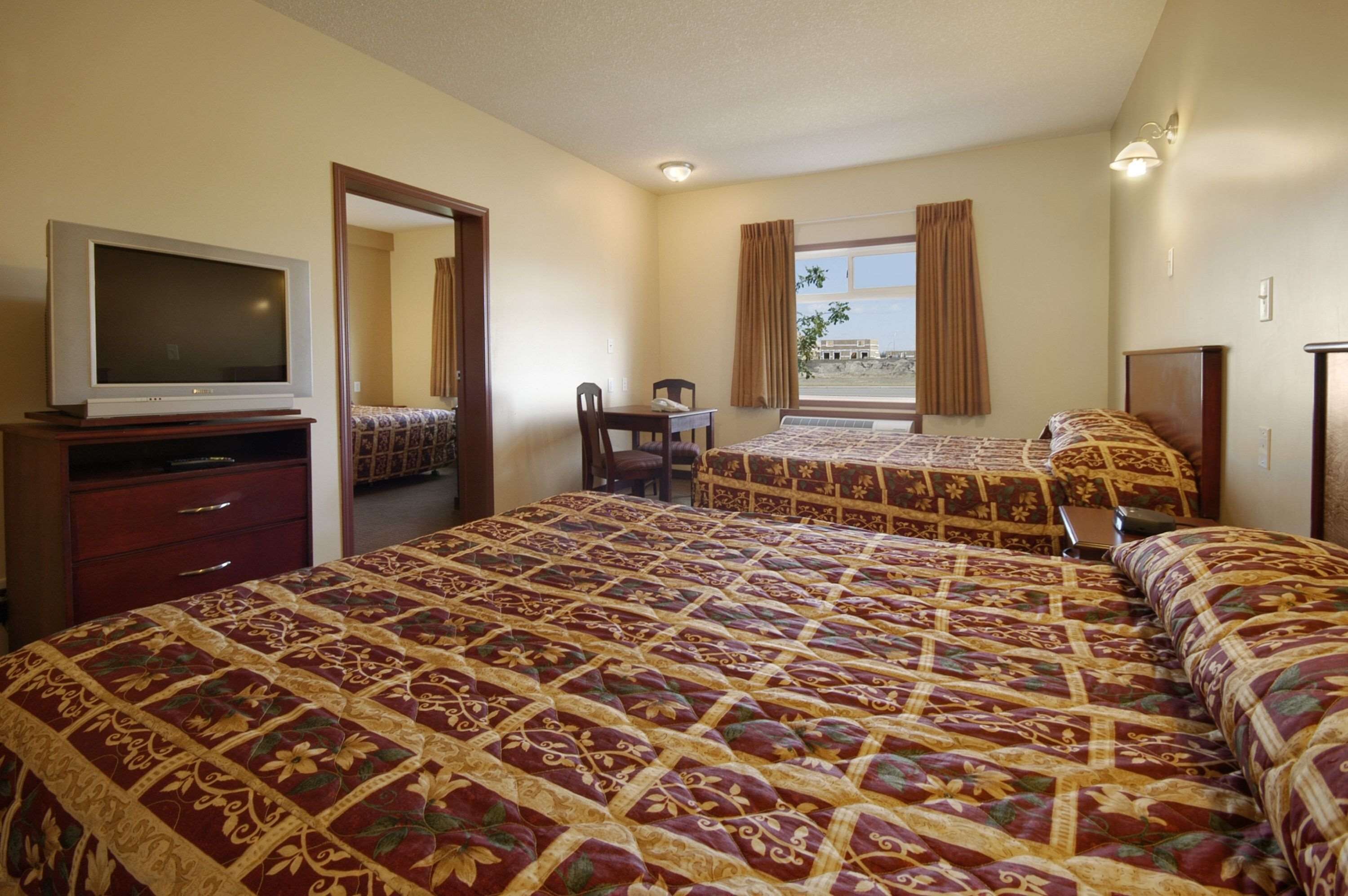 A hotel room with two beds, a TV, a desk, and a chair.