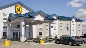 Un hotel Super 8 con zona de estacionamiento techada y varios coches aparcados.