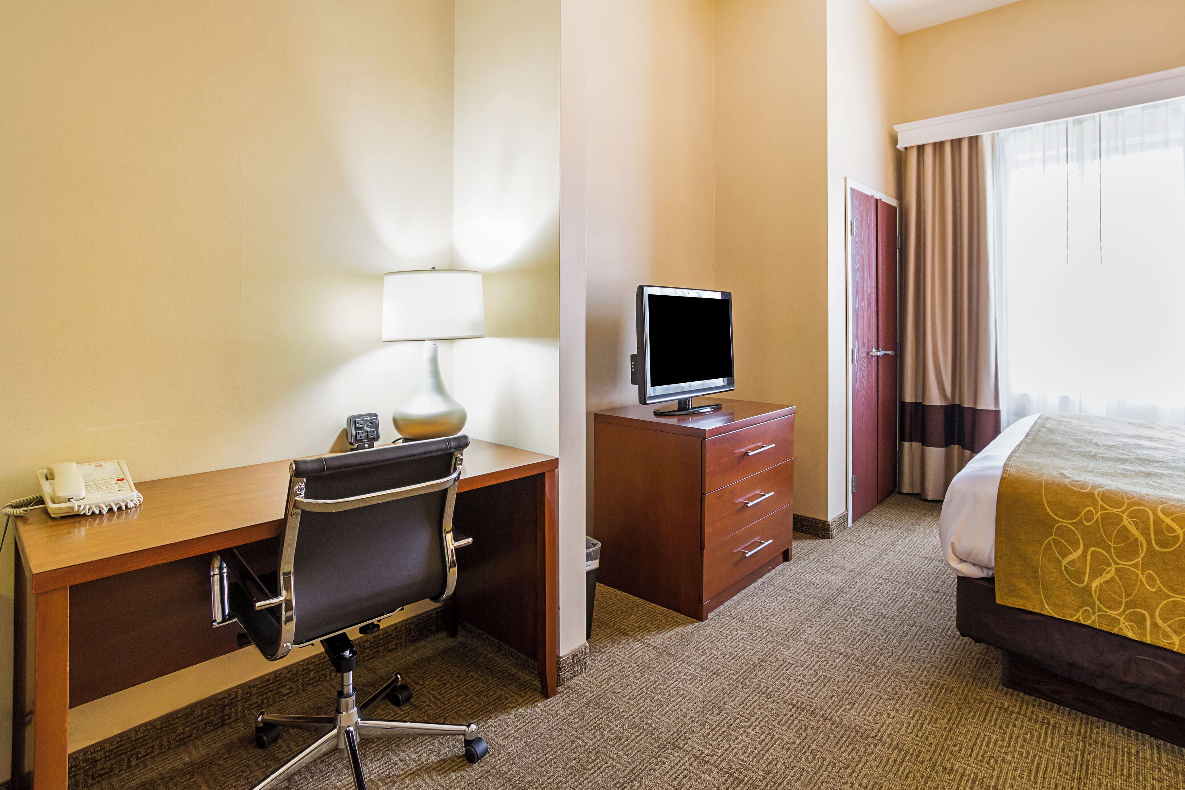 Une chambre d’hôtel équipée d’un bureau, d’une chaise, d’une télévision et d’un lit.