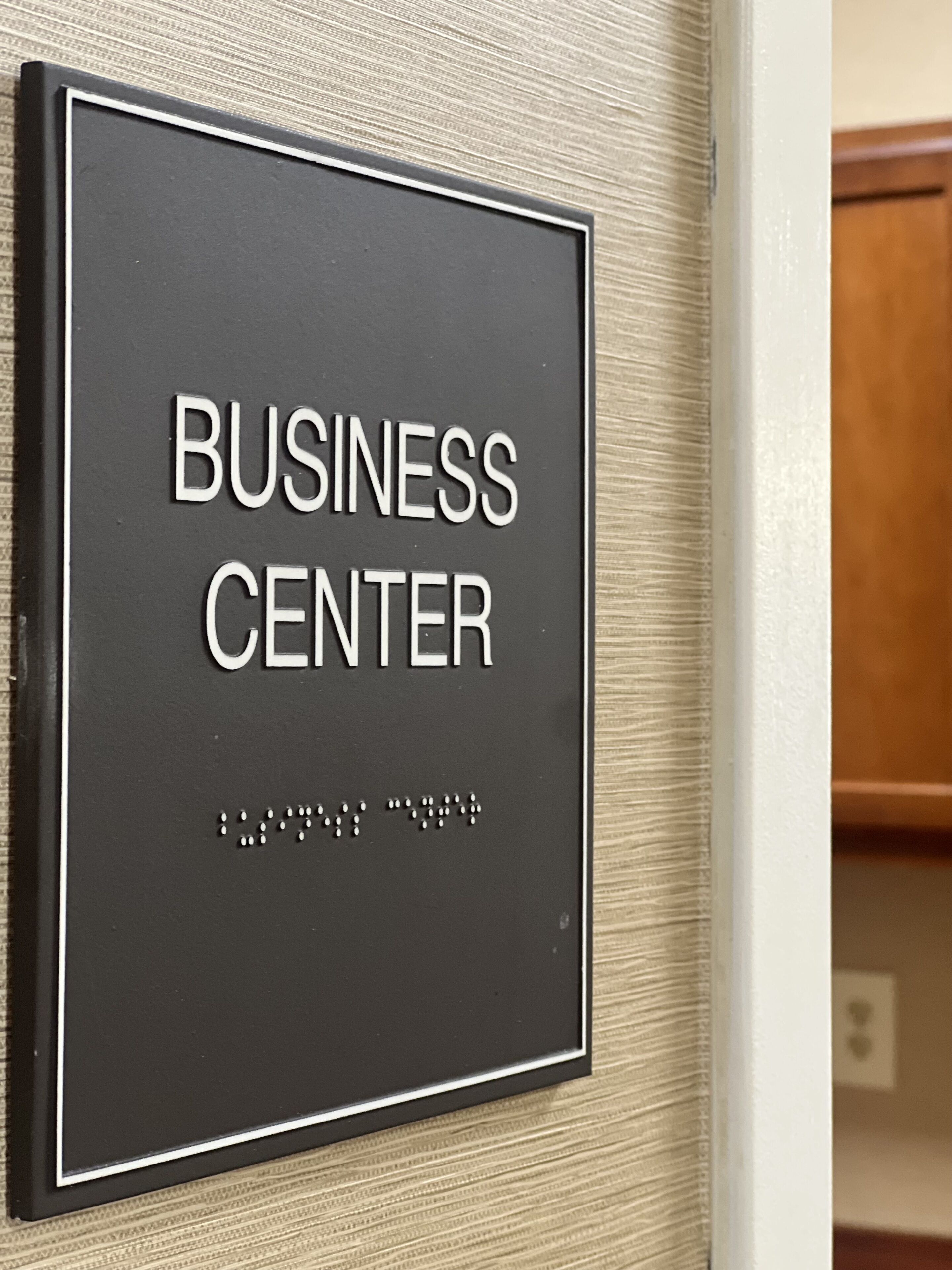 Ein Schild mit der Aufschrift 'BUSINESS CENTER' und darunter Brailleschrift.