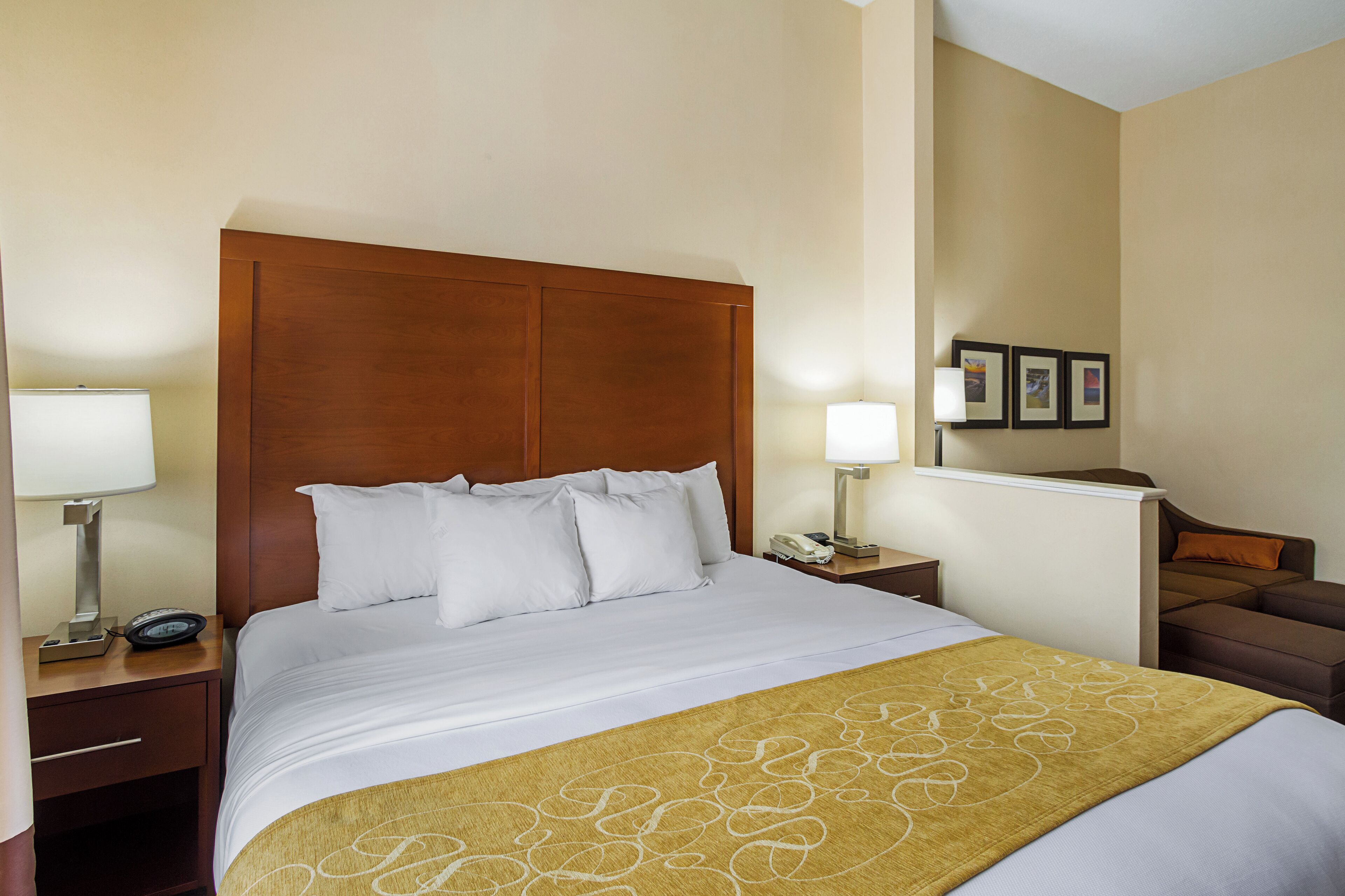 A hotel room with a large bed, two bedside tables, a nightstand, a desk, and a chair.