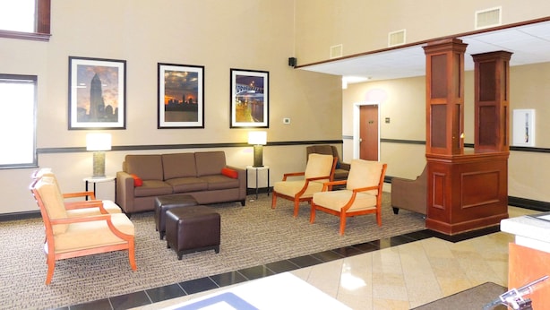 A lobby with a sofa, armchairs, a wooden pillar, and framed pictures on the wall. - Comfort Suites Twinsburg (Twinsburg)