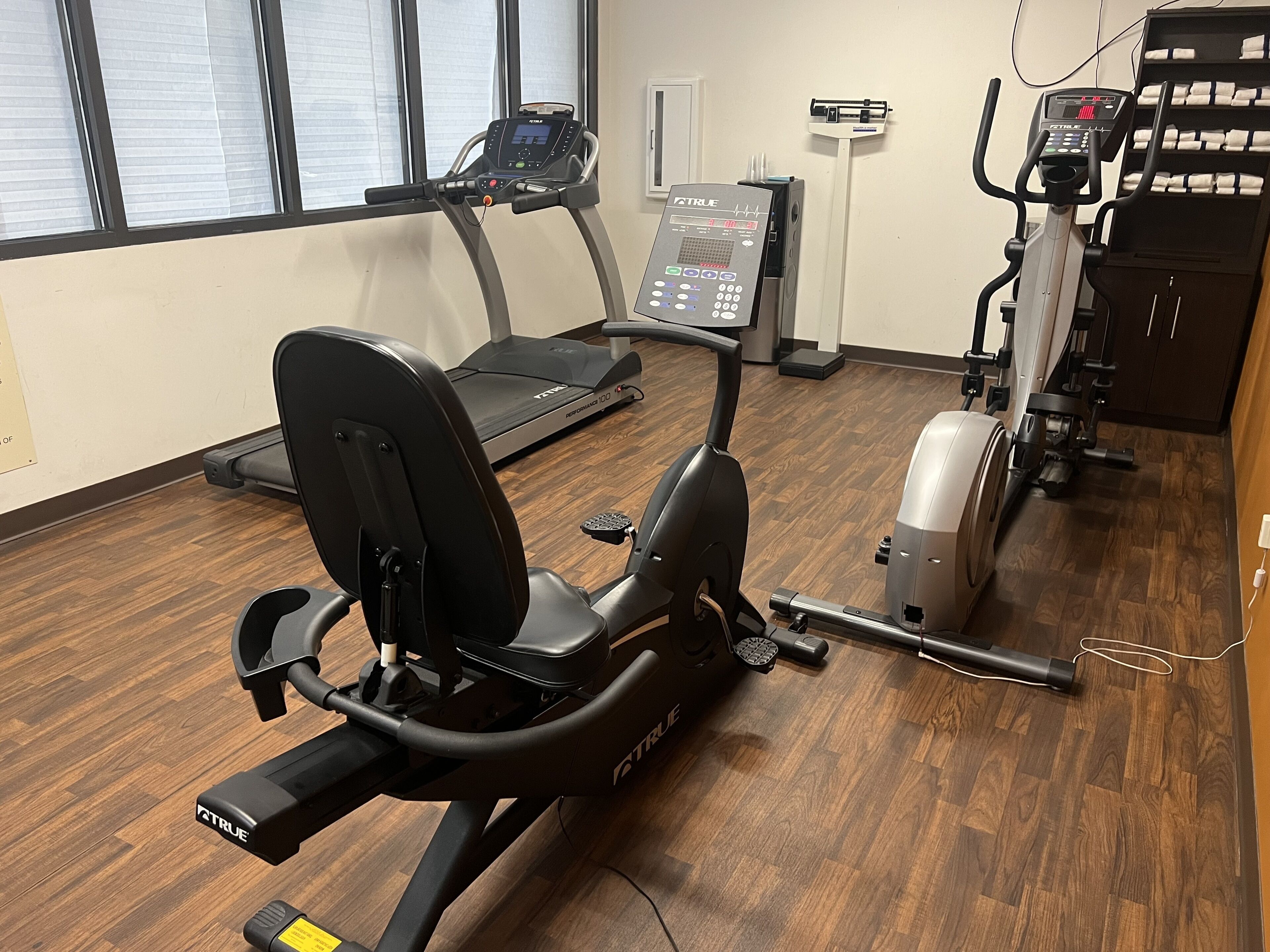 A gym with various exercise equipment including a stationary bike, treadmill, and elliptical machine.