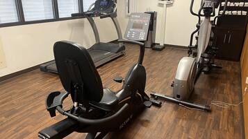 A gym with various exercise equipment including a stationary bike, treadmill, and elliptical machine.