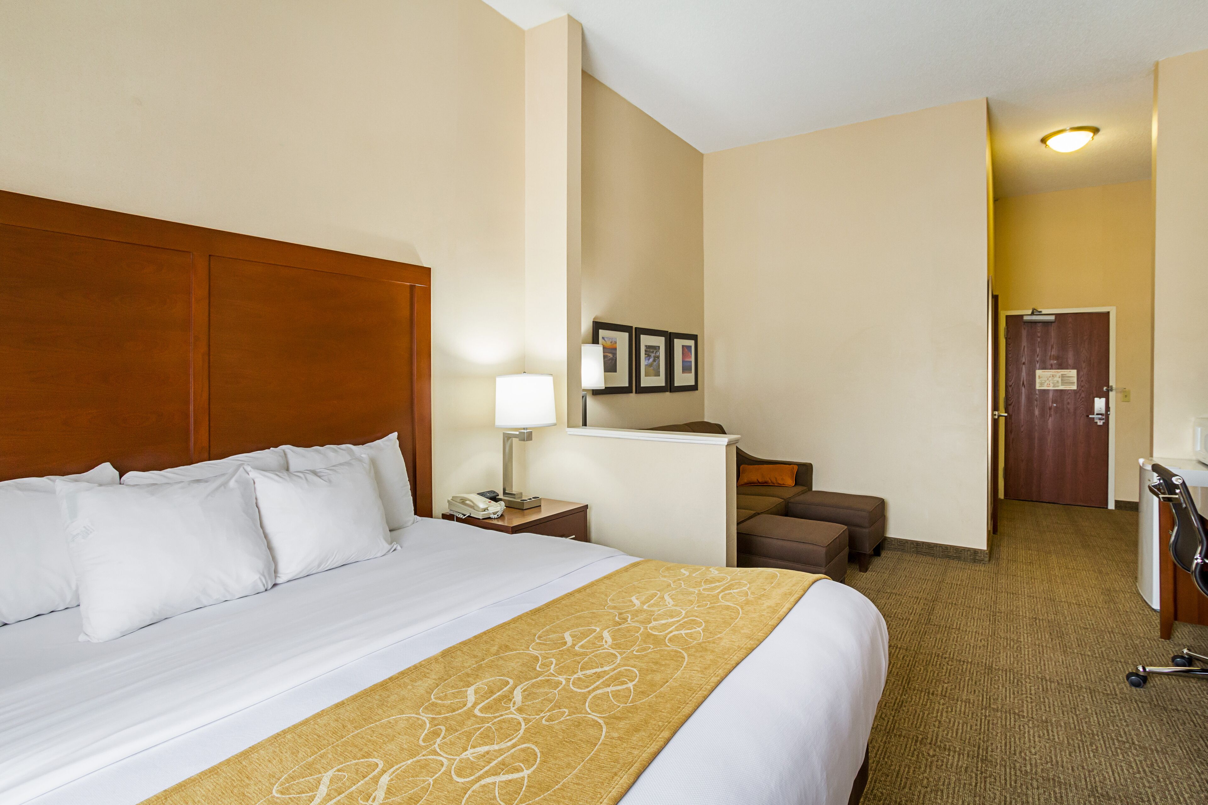 A hotel room with a large bed, a desk, a chair, and a door.