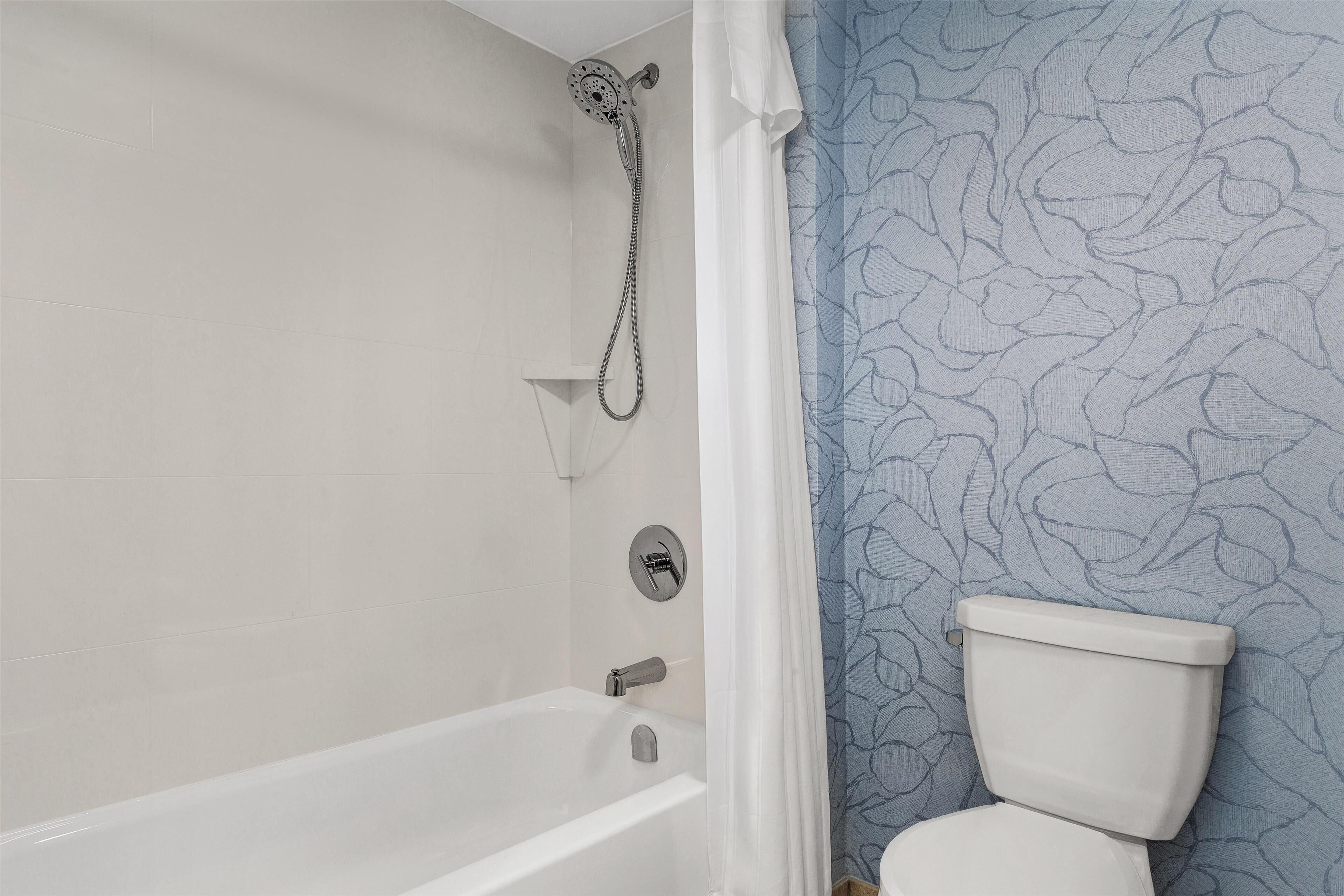 A bathroom with a bathtub, shower, and toilet.