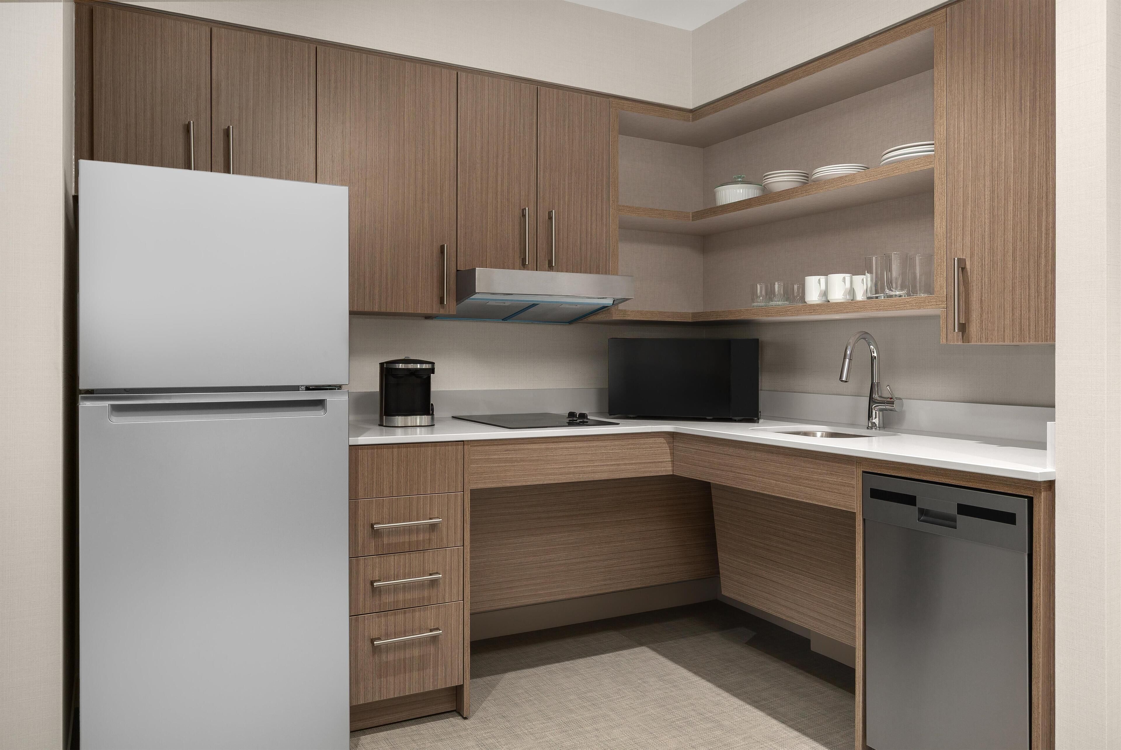 Una cocina moderna con armarios de madera, un refrigerador blanco, un microondas negro y un lavavajillas.