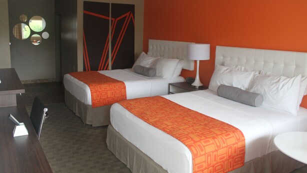Een hotelkamer met twee bedden, een bureau en een stoel.
