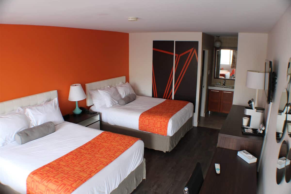 Une chambre d’hôtel avec deux lits, un bureau, un miroir et une armoire.