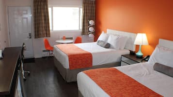 Une chambre d’hôtel avec deux lits, un bureau, une chaise, une petite table et une fenêtre avec des rideaux.