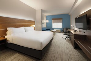 Habitación de hotel con una cama grande, un escritorio con silla, televisión y ventana con persianas.