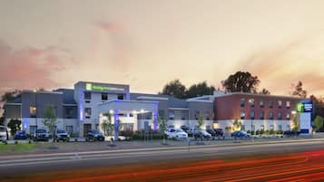A Holiday Inn Express & Suites hotel with a modern design, featuring multiple parking spaces and a well-lit entrance.