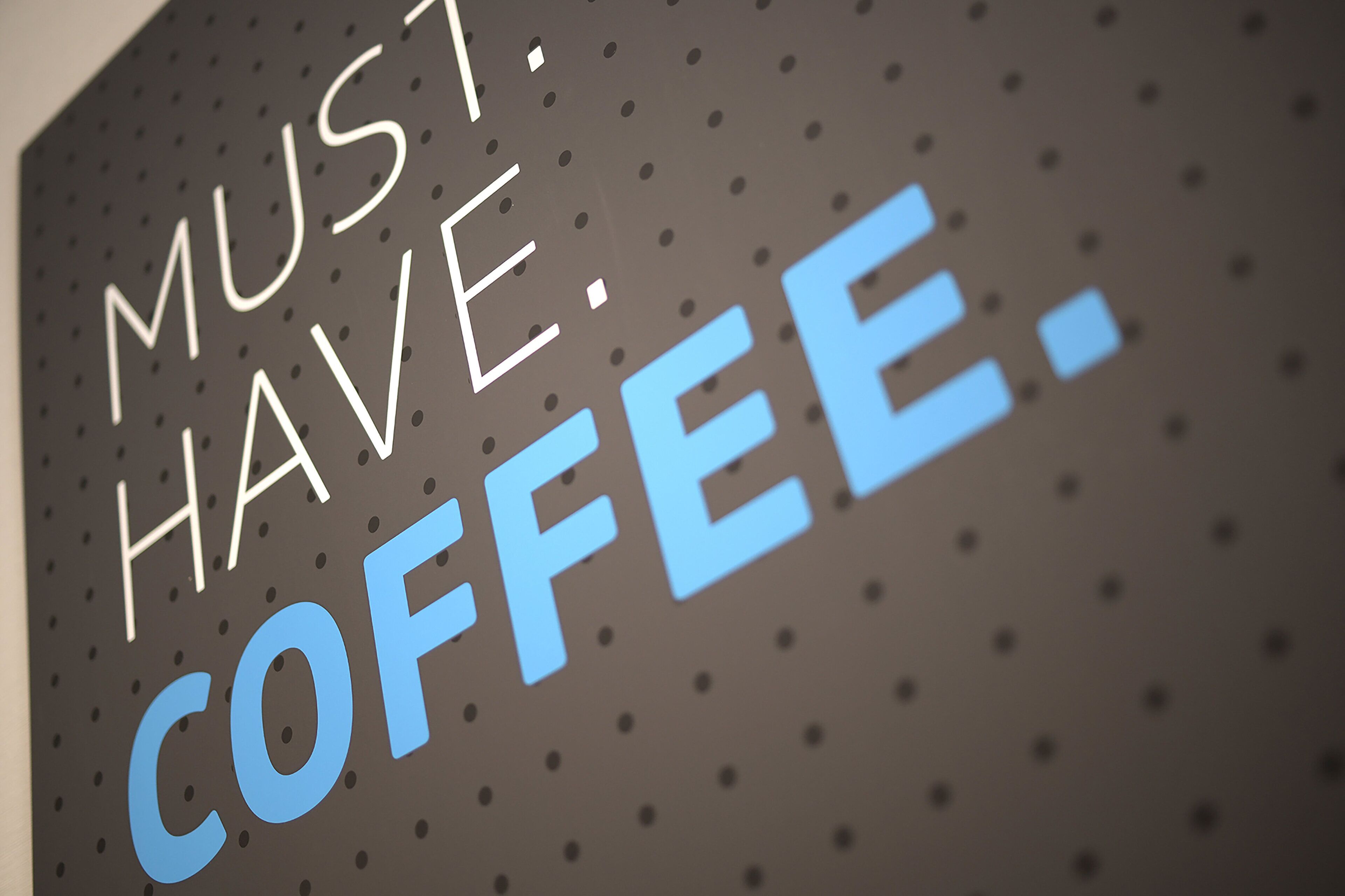 A wall with the text "MUST HAVE COFFEE."