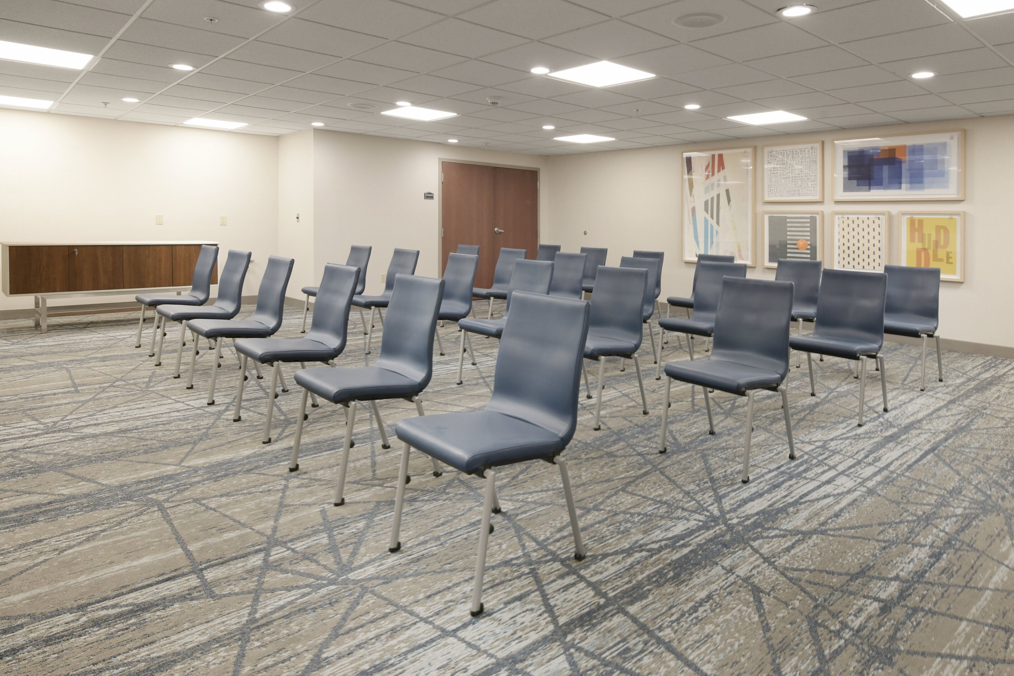 Une salle de conférence avec des rangées de chaises, un banc en bois et une porte.