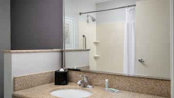 A bathroom with a granite countertop sink, a mirror, a towel rack, and a shower curtain.