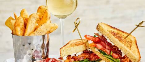 A plate with a grilled sandwich, a glass of white wine, and a cup of fries.