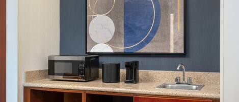 A kitchenette with a microwave, coffee maker, and sink.