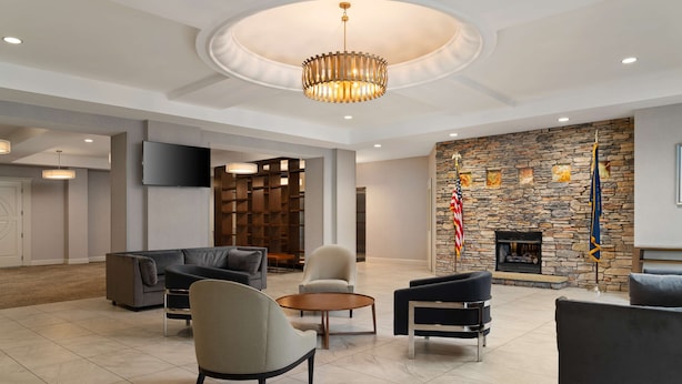 A spacious lobby with a stone fireplace, modern furniture, and a television mounted on the wall. - DoubleTree by Hilton Pittsburgh Airport (Coraopolis)