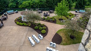 An outdoor patio area with seating arrangements, a small garden, and a paved walkway. - DoubleTree by Hilton Pittsburgh Airport (Coraopolis)