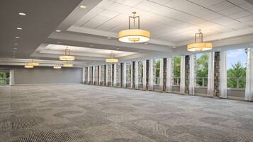 A spacious conference room with a patterned carpet, large windows with stone frames, and multiple hanging pendant lights.