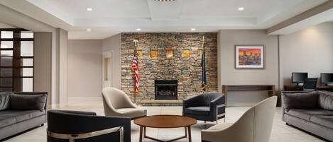 A modern living room with a stone fireplace, comfortable seating, and a chandelier.