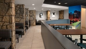 A restaurant with stone walls, a curved counter, and a cityscape mural. - DoubleTree by Hilton Pittsburgh Airport (Coraopolis)