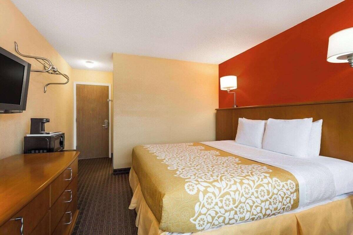 A hotel room with a bed, a TV, a coffee maker, and a desk.
