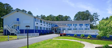 A large, two-story building with a blue and white exterior, a covered front porch, and a staircase leading to the entrance.