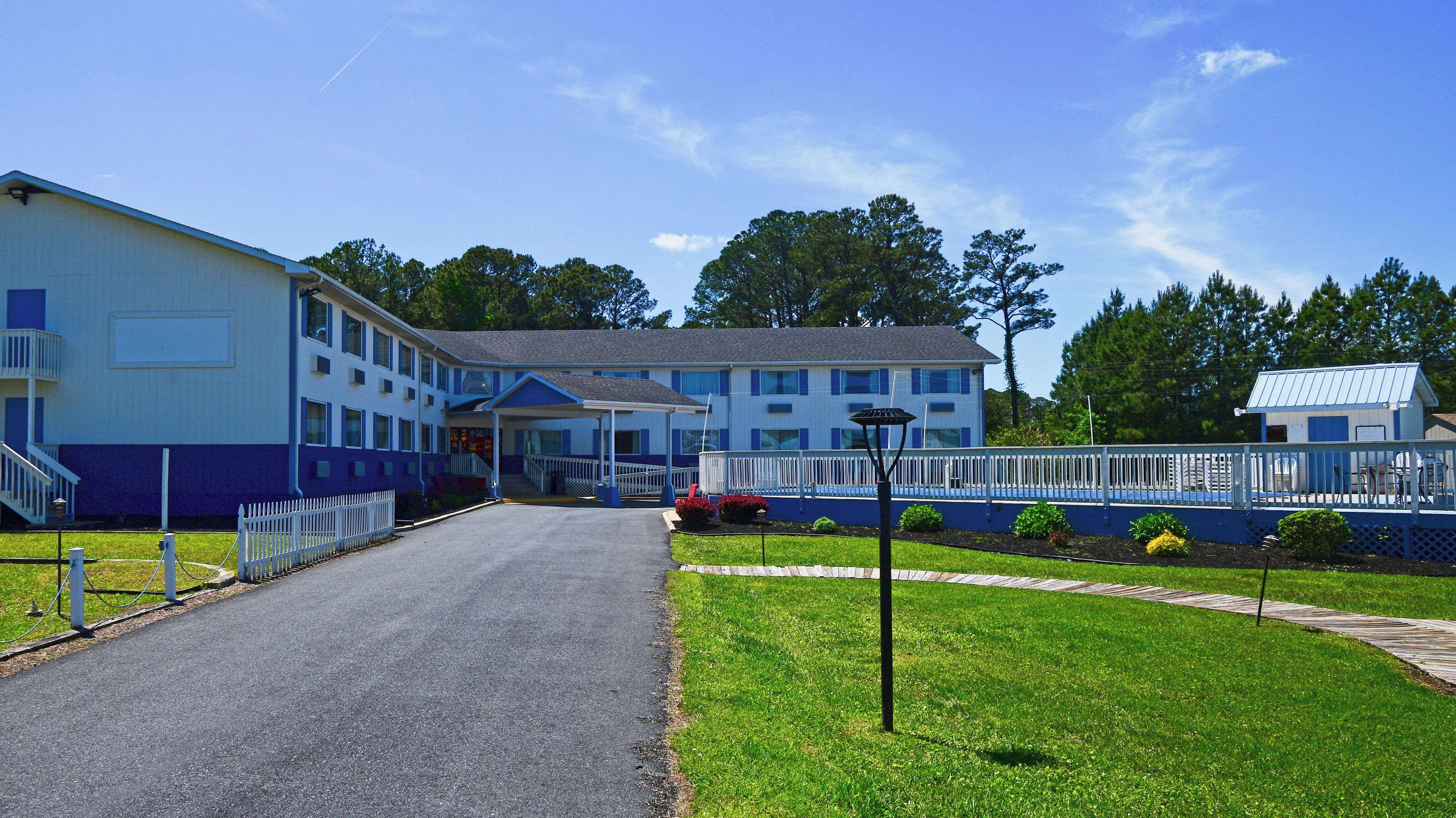 Un motel doté d’une entrée principale, d’un passage couvert et d’un parking clôturé.
