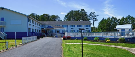 A motel with a central entrance, a covered walkway, and a fenced parking area.