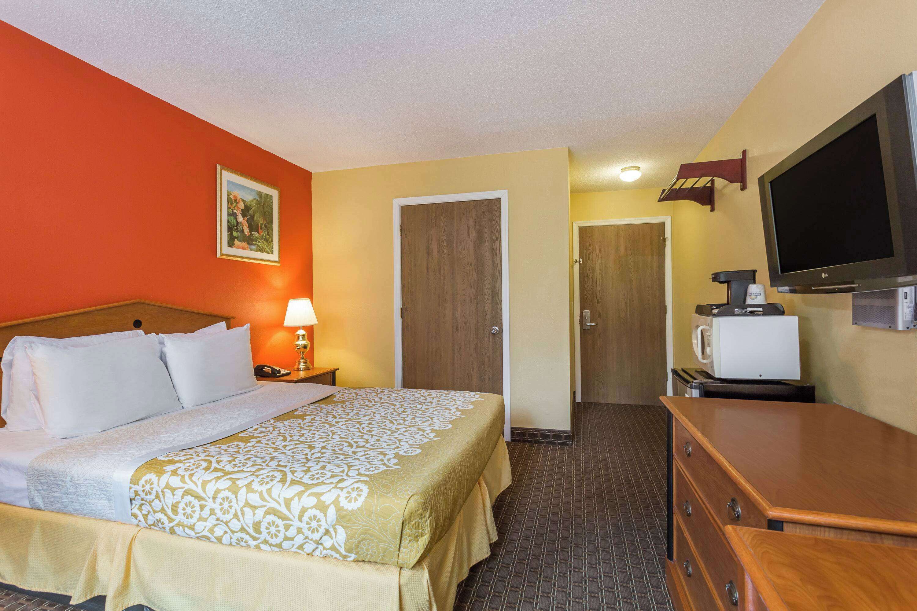 A hotel room with a bed, a television, a microwave, and a dresser.