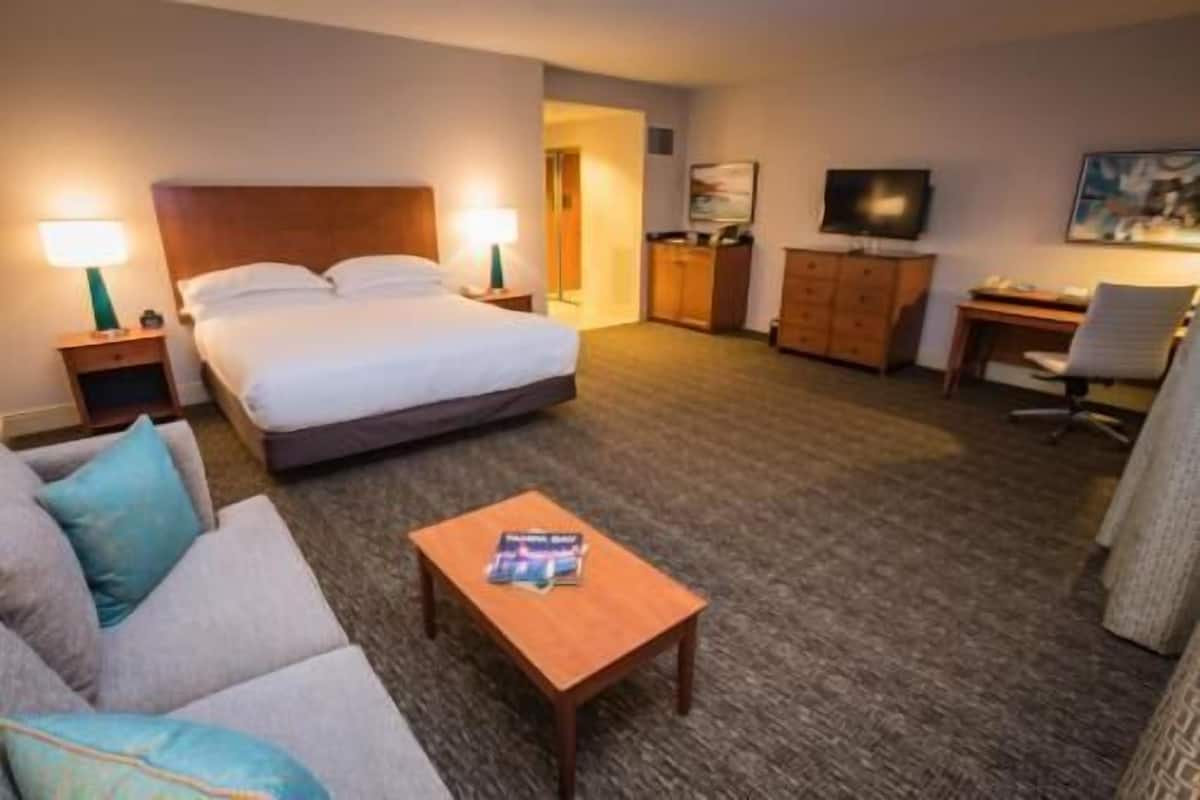 A hotel room with a bed, a desk, a television, a sofa, and a coffee table.