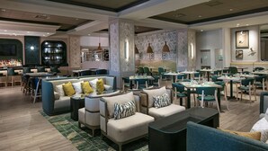 A modern hotel lobby with seating areas, a bar, and a dining section. - Hilton St. Petersburg Carillon Park (St. Petersburg)