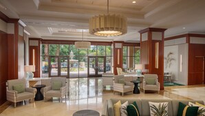 A spacious lobby with a large sofa, armchairs, and a coffee table. There are large windows offering a view of the outdoors. - Hilton St. Petersburg Carillon Park (St. Petersburg)