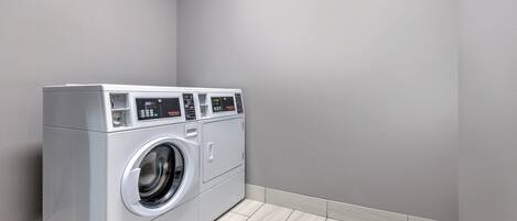 A compact, modern laundry room with a front-loading washer and dryer, minimalistic design, and light-colored flooring.