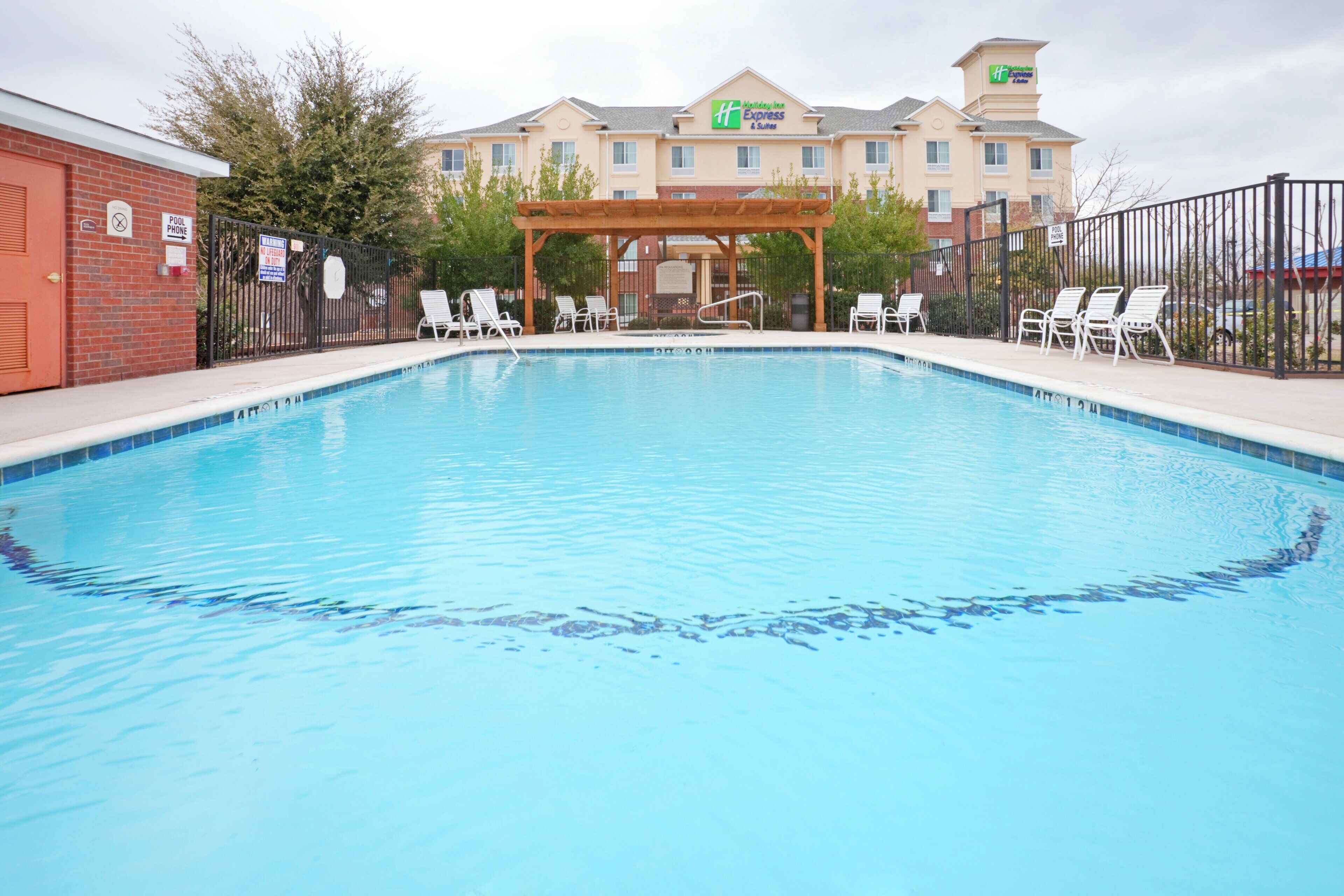 A swimming pool with lounge chairs and a hotel building in the background.