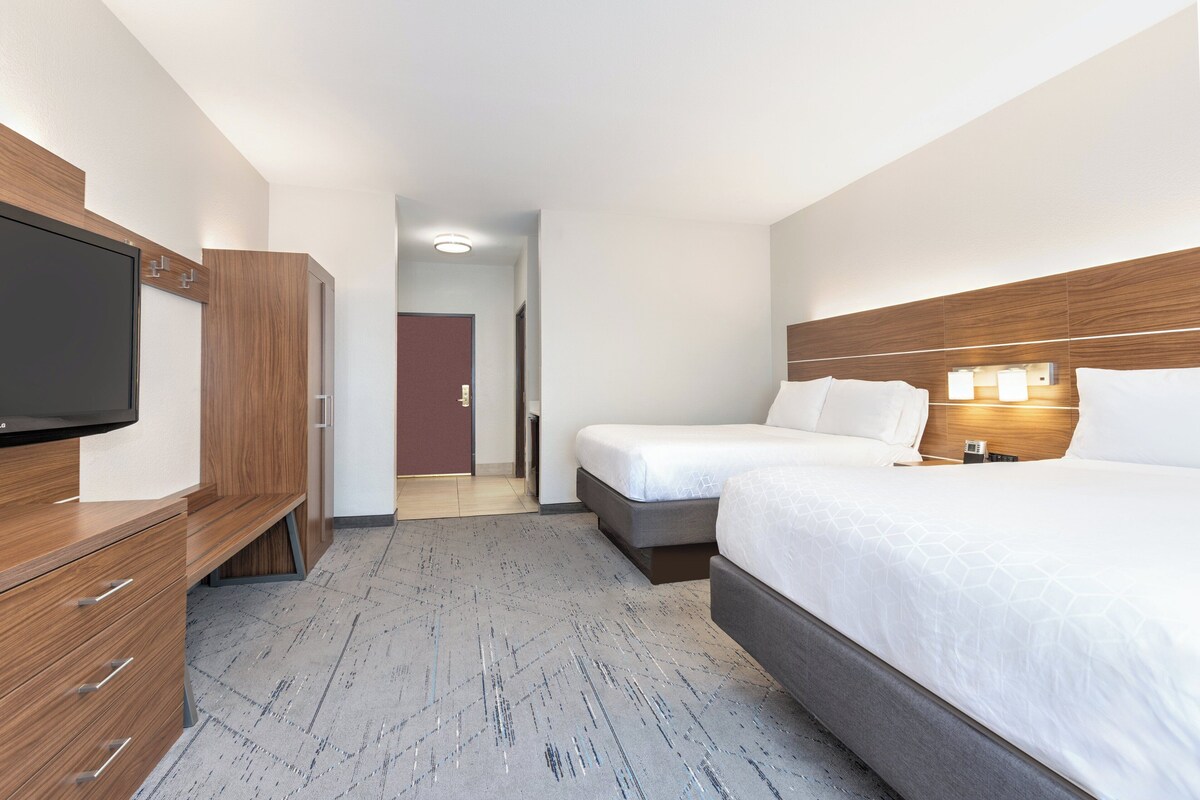 Een hotelkamer met een bed, een televisie, een bureau en een kledingkast.