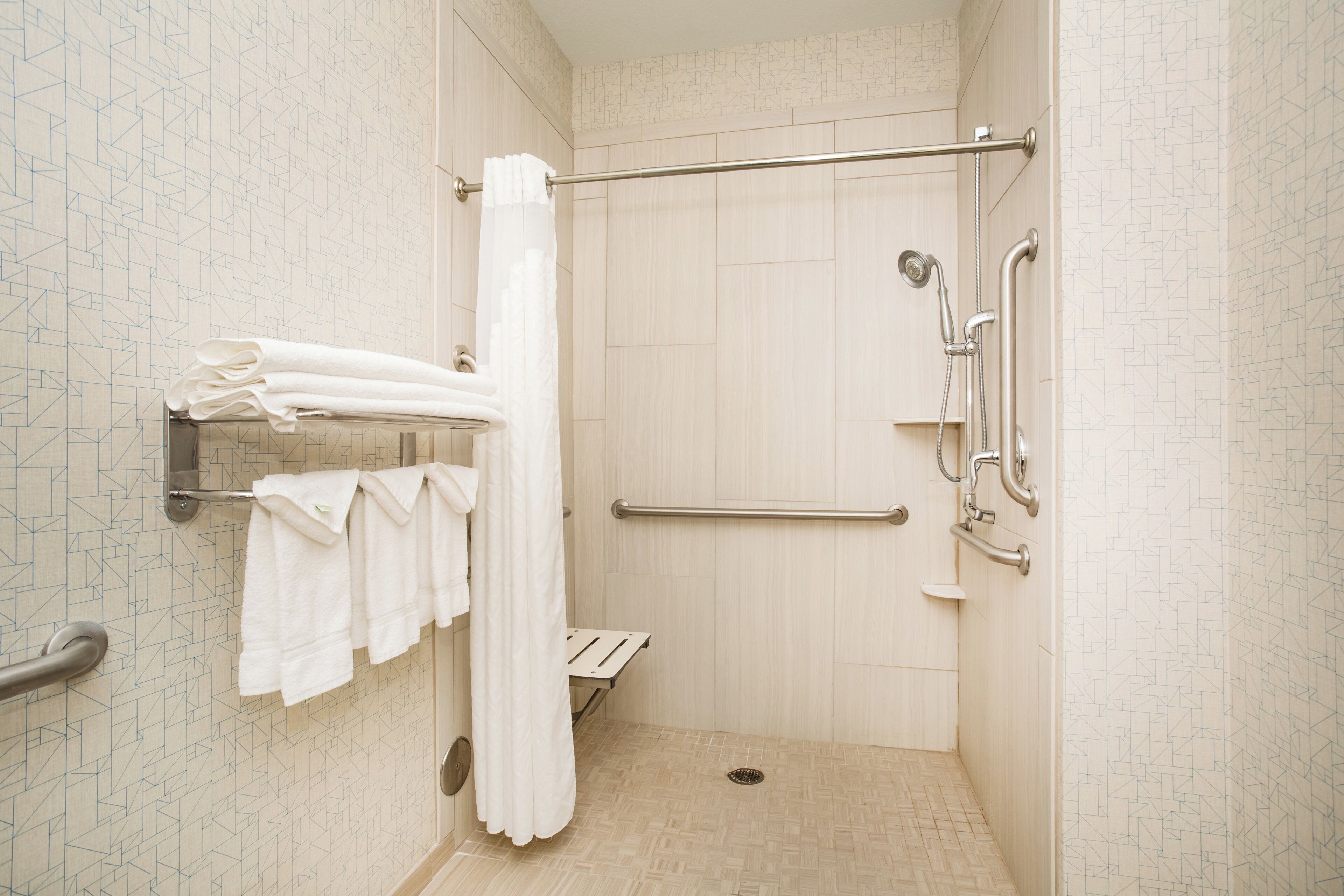 A shower area with a grab bar, a towel rack, and a showerhead.