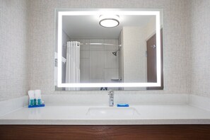 Une salle de bain avec un grand miroir, un lavabo et une douche.