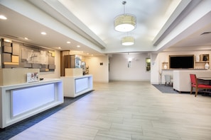 A hotel reception area with a modern design, including a reception desk, a refrigerator, and a flat-screen TV. - Holiday Inn Express Hotel & Suites Ft. Collins by IHG (Fort Collins)