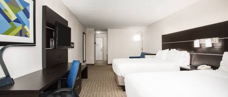 A hotel room with a desk, chair, television, two beds, and a door leading to another room.
