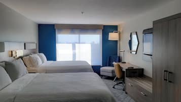 A hotel room with two beds, a desk, a chair, a TV, and a wardrobe.