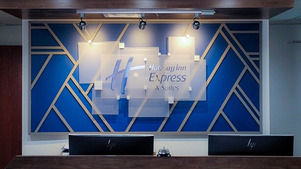 A reception desk with a sign reading "Holiday Inn Express & Suites" and a geometric wall design. - Holiday Inn Express Hotel & Suites Enid - Highway 412 by IHG (Enid)
