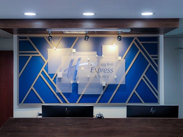 A reception desk with a sign reading "Holiday Inn Express & Suites" and a geometric wall design. - Holiday Inn Express Hotel & Suites Enid - Highway 412 by IHG (Enid)