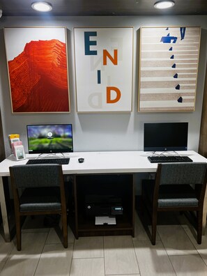 A workspace with two monitors, a keyboard, and a mouse on a white desk. There are two chairs, a printer, and framed artwork on the wall. - Holiday Inn Express Hotel & Suites Enid - Highway 412 by IHG (Enid)