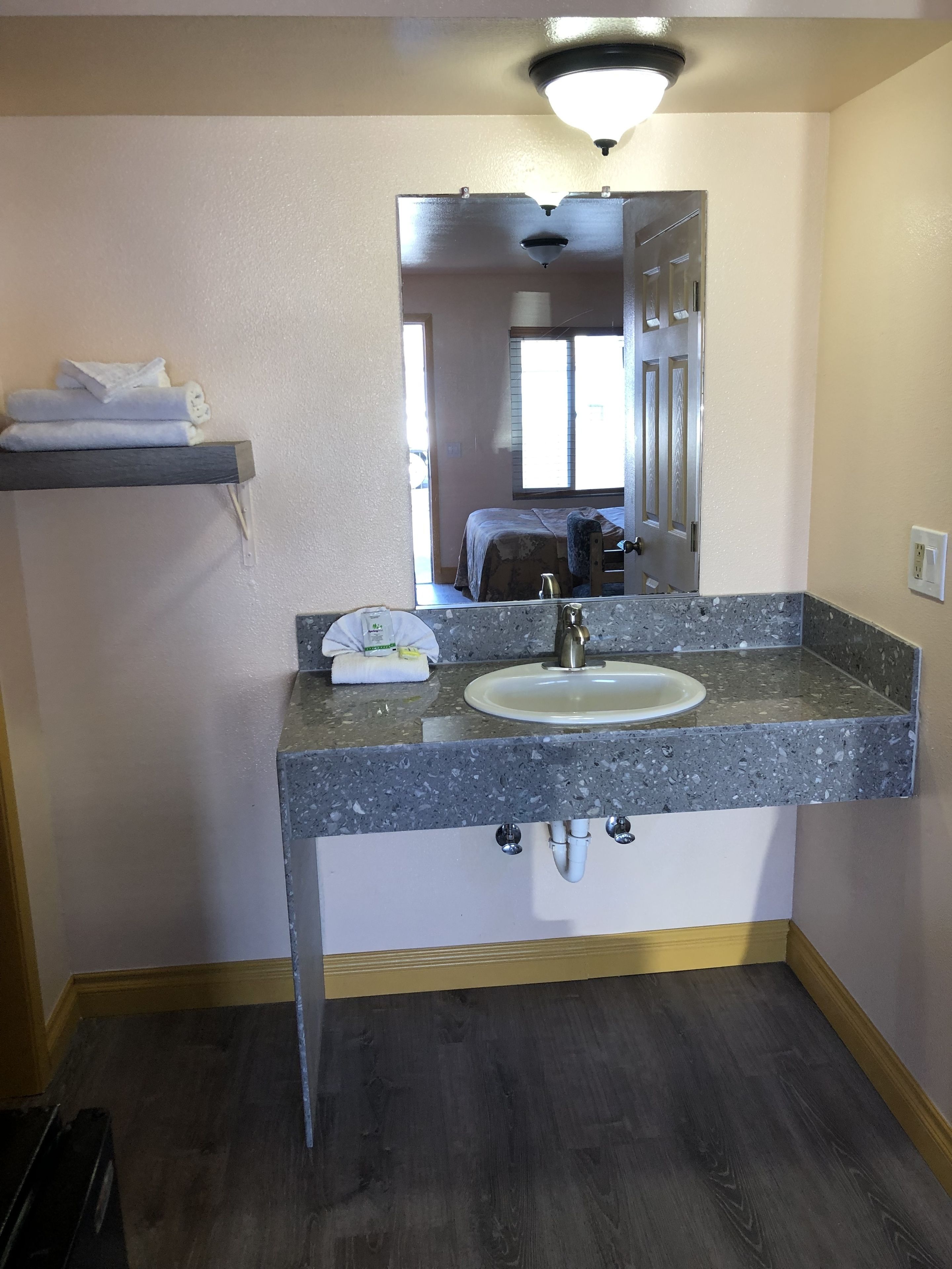 A bathroom with a granite countertop sink, a mirror, and a towel rack.