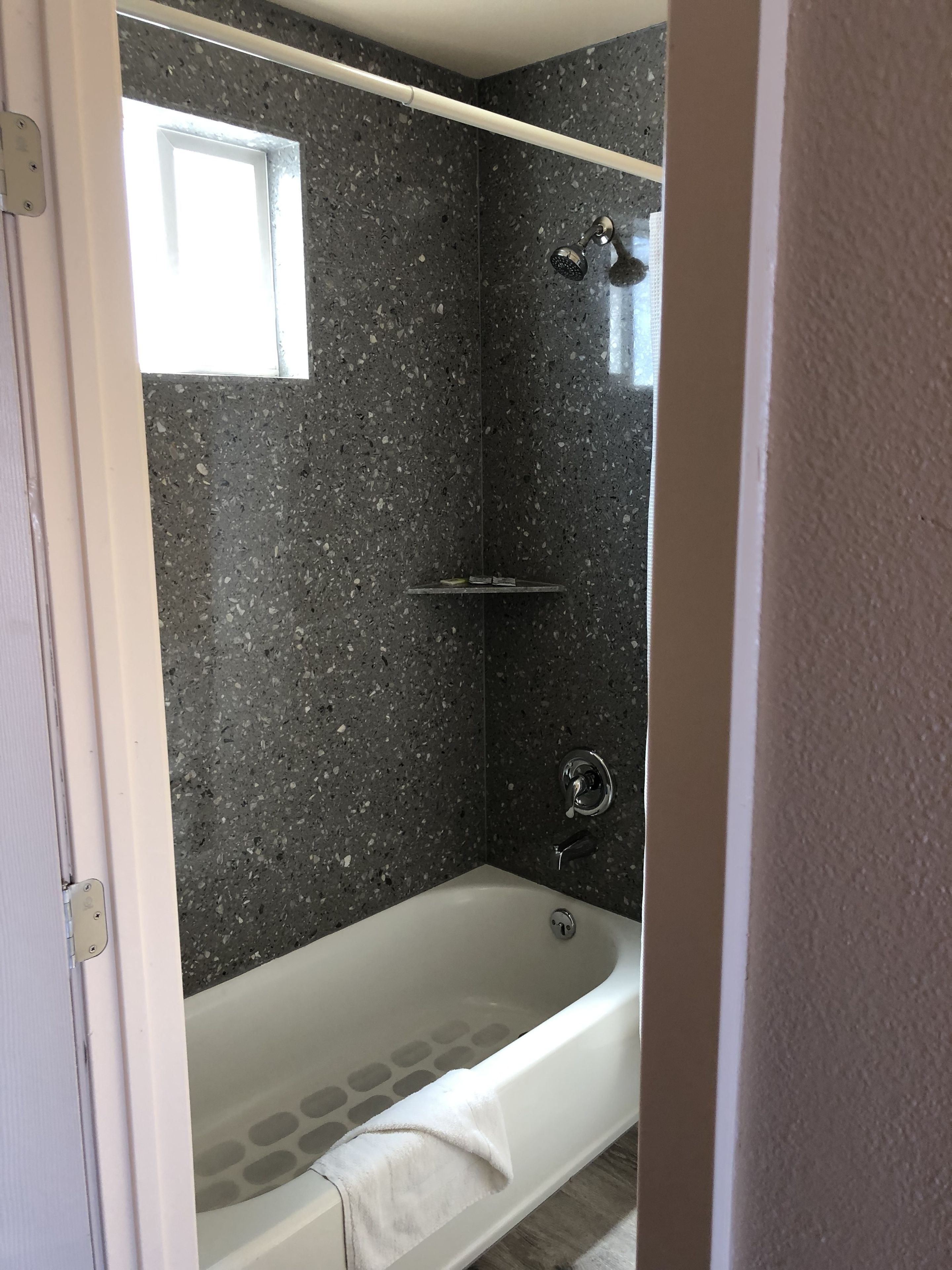 A bathroom with a bathtub, a shower, and a window.