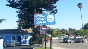 Une enseigne « Blue Seal Inn » avec le logo de l’établissement, un bâtiment de motel et un palmier.