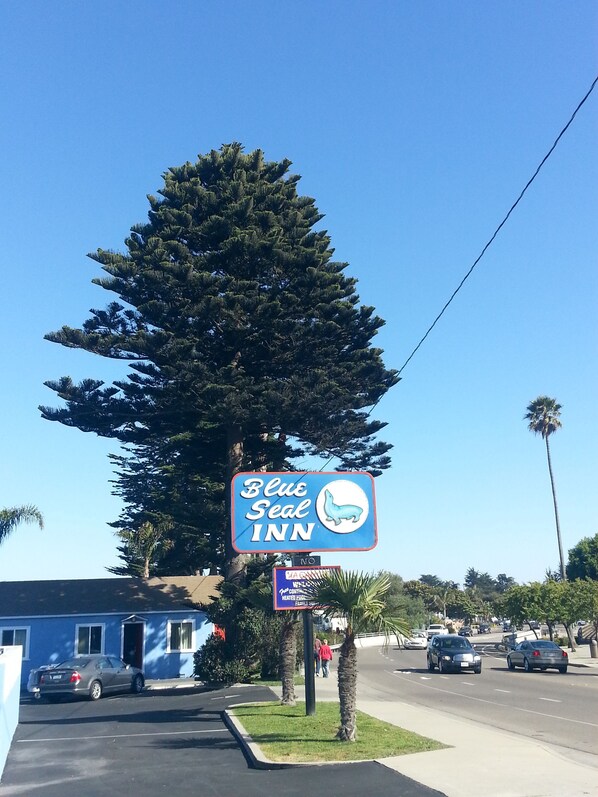 Letrero de Blue Seal Inn con el logo de un sello, un edificio de motel y una palmera.